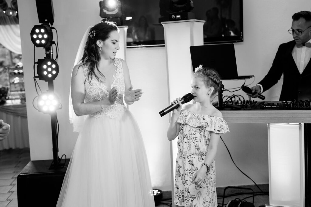 Karaoke na wesele -  to świetny pomysł na imprezę.
Pani młoda razem z najmłodszym uczestnikiem wesela śpiewają do mikrofonu. A wszystko to na weselu.
